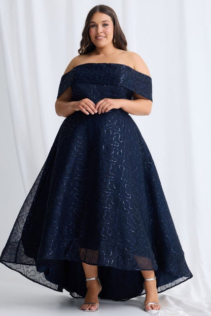 Woman wearing a navy off-shoulder lace dress against a white background