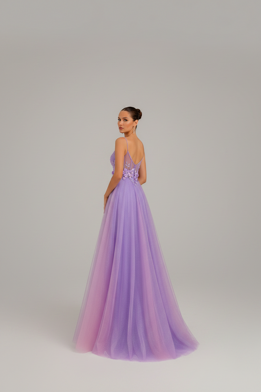 Woman in a two-tone pink and purple dress standing on steps with decorative railings.