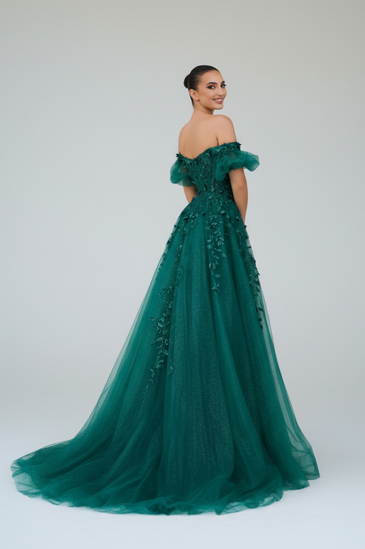 Woman in a green evening gown standing outside a building with decorative elements.