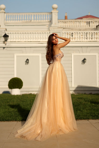 Woman in a peach evening gown standing in front of a white building with columns.