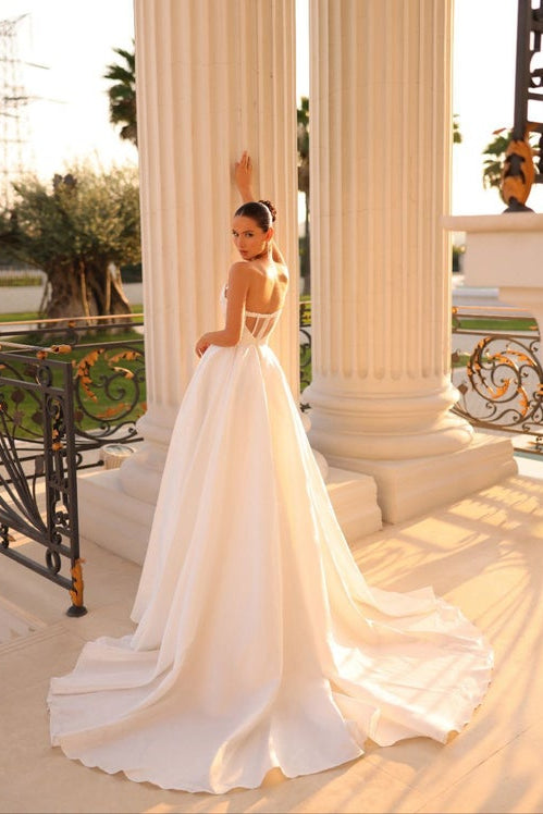 Woman in a white wedding dress standing in front of classical columns.