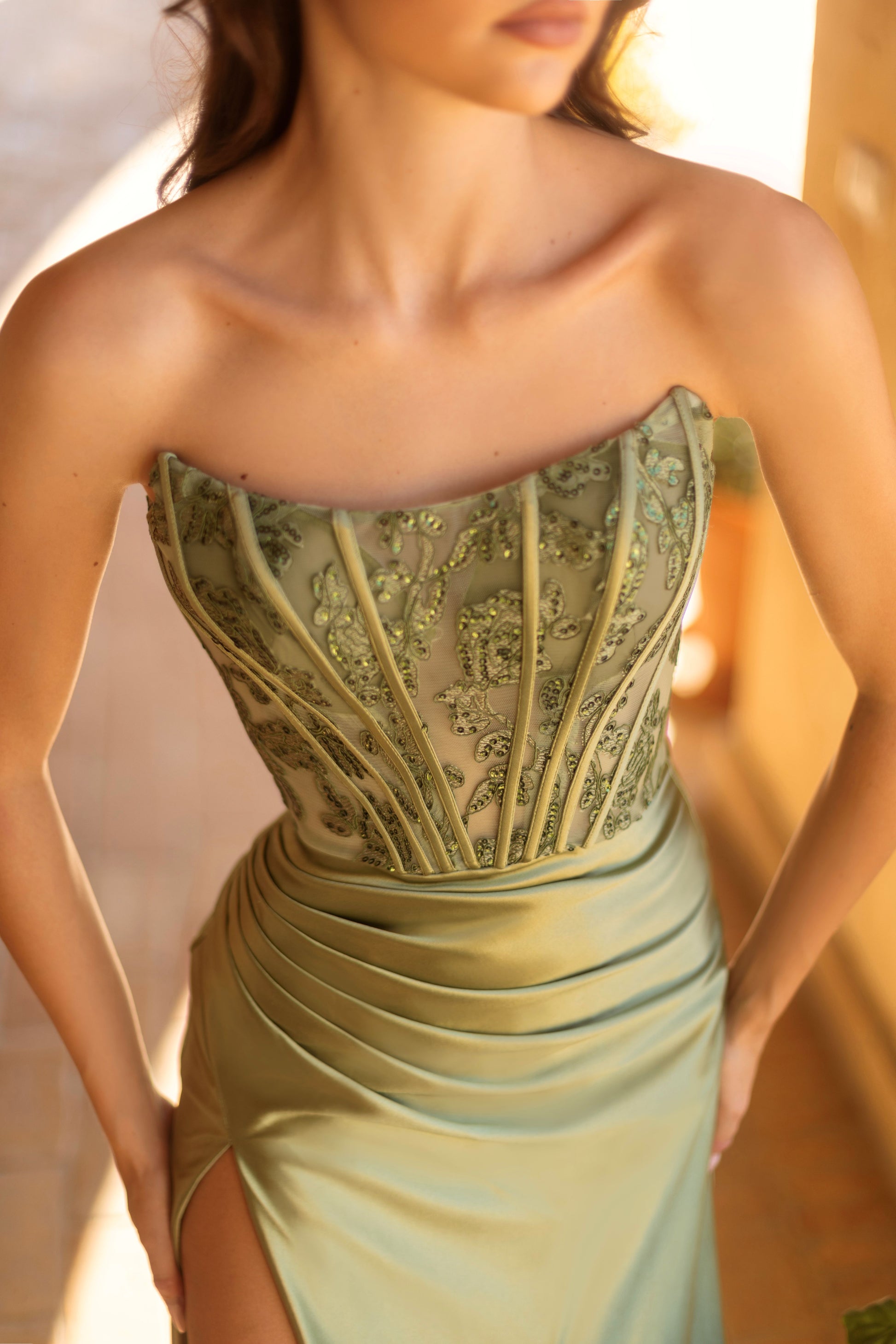 Woman wearing a strapless, embellished green dress with a blurred background