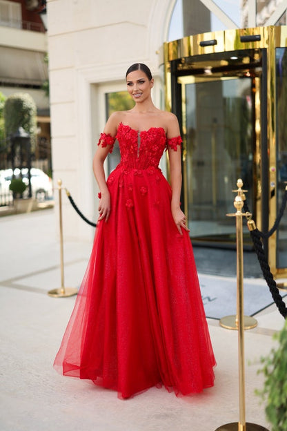 Woman in a red evening gown standing in front of a hotel entrance.