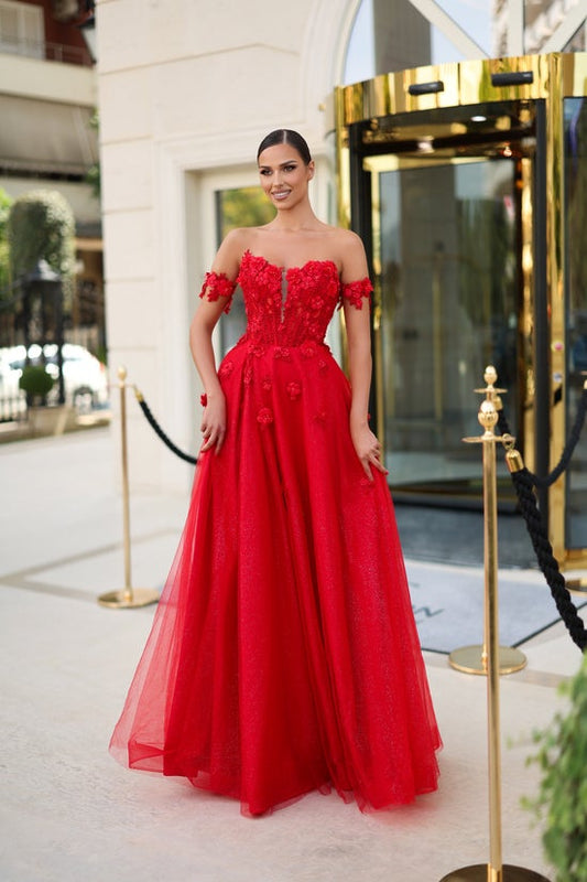 Woman in a red evening gown standing in front of a hotel entrance.