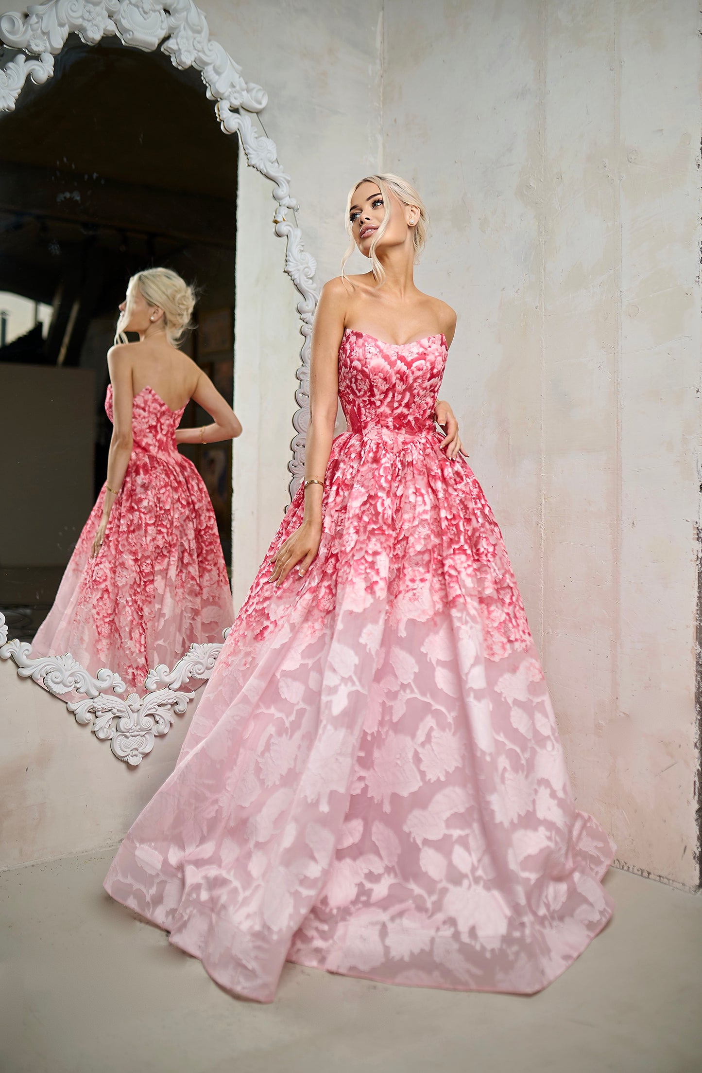 Woman wearing a pink floral dress standing in front of a mirror.