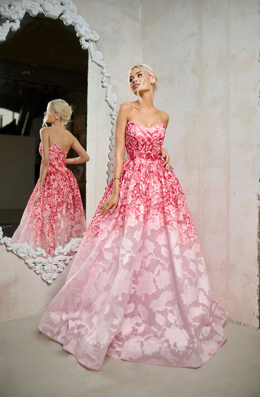 Woman wearing a pink floral dress standing in front of a mirror.