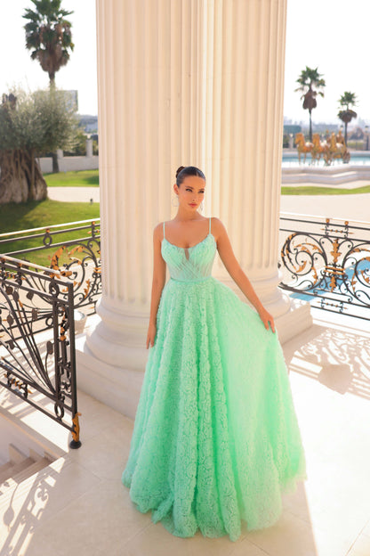 Woman in a light green evening gown standing on a balcony with a scenic background