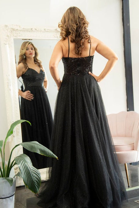 Woman in a black evening gown standing in front of a mirror.