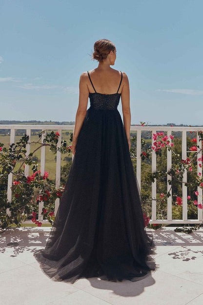 Woman in a black evening gown standing on a balcony with floral decorations.