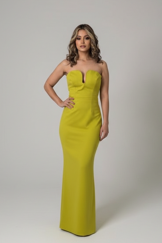 A woman modeling a strapless, fitted floor-length gown in a bright chartreuse yellow-green color, standing against a neutral light gray studio backdrop.